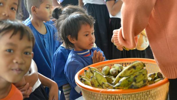 Des enfants des paillotes reçoivent des bananes pour le gouter