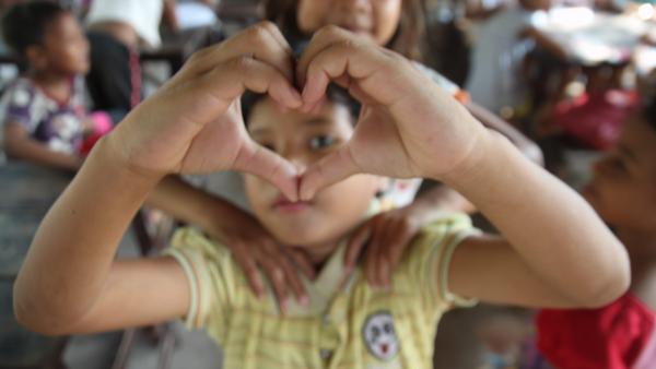 Une petite fille fait un coeur avec ses mains