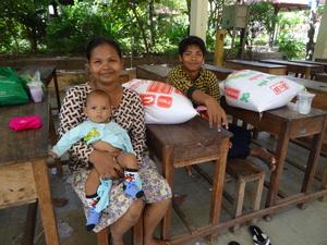 Une mère et ses deux enfants avec le riz reçu de la part de PSE