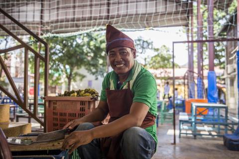Un employé de la cantine de PSE sourit pendant qu'il cuisine Portrait d'un cuisinier de la cantine de PSE